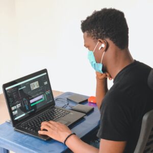 Man wearing a mask whilst working on his laptop